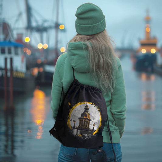 Person trägt schwarzen Rucksack mit Wasserkunst-Wismar-Motiv am Hafen