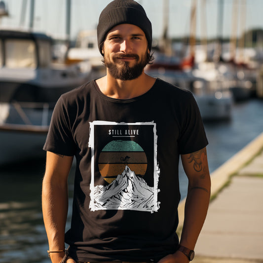 Worawo T-Shirt „Still Alive“ in schwarz mit Bergmotiv, Retro-Sonne und Still-Alive-Schriftzug – am Model im Hafen