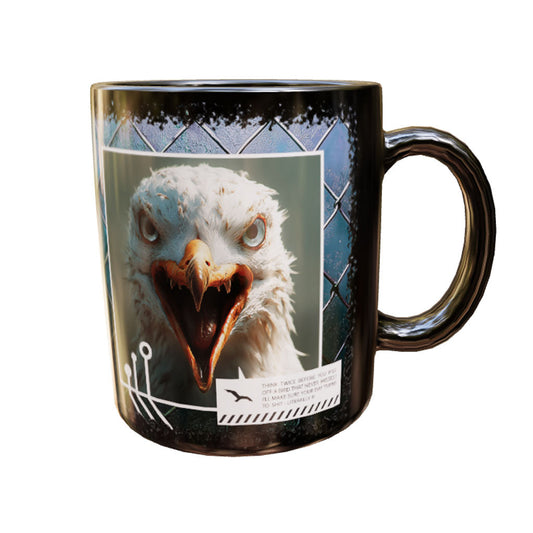 Schwarze Keramiktasse Psychogull mit schreiender weiß-grauer Möwe und weit geöffnetem Schnabel vor blauem Gitter – Produktansicht
